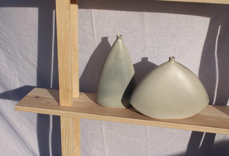 The vases on a pine shelf in raking sunlight