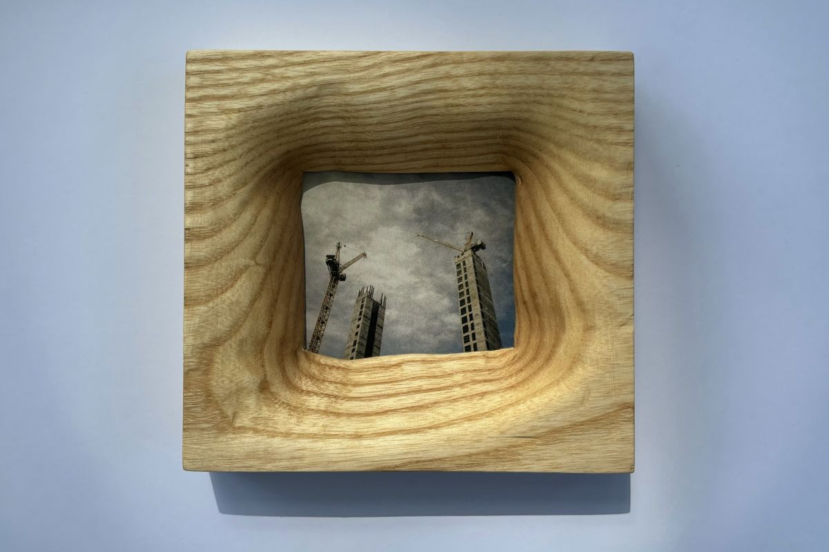 Ash frame with flowing grain, holding a photo of cranes and tower blocks
