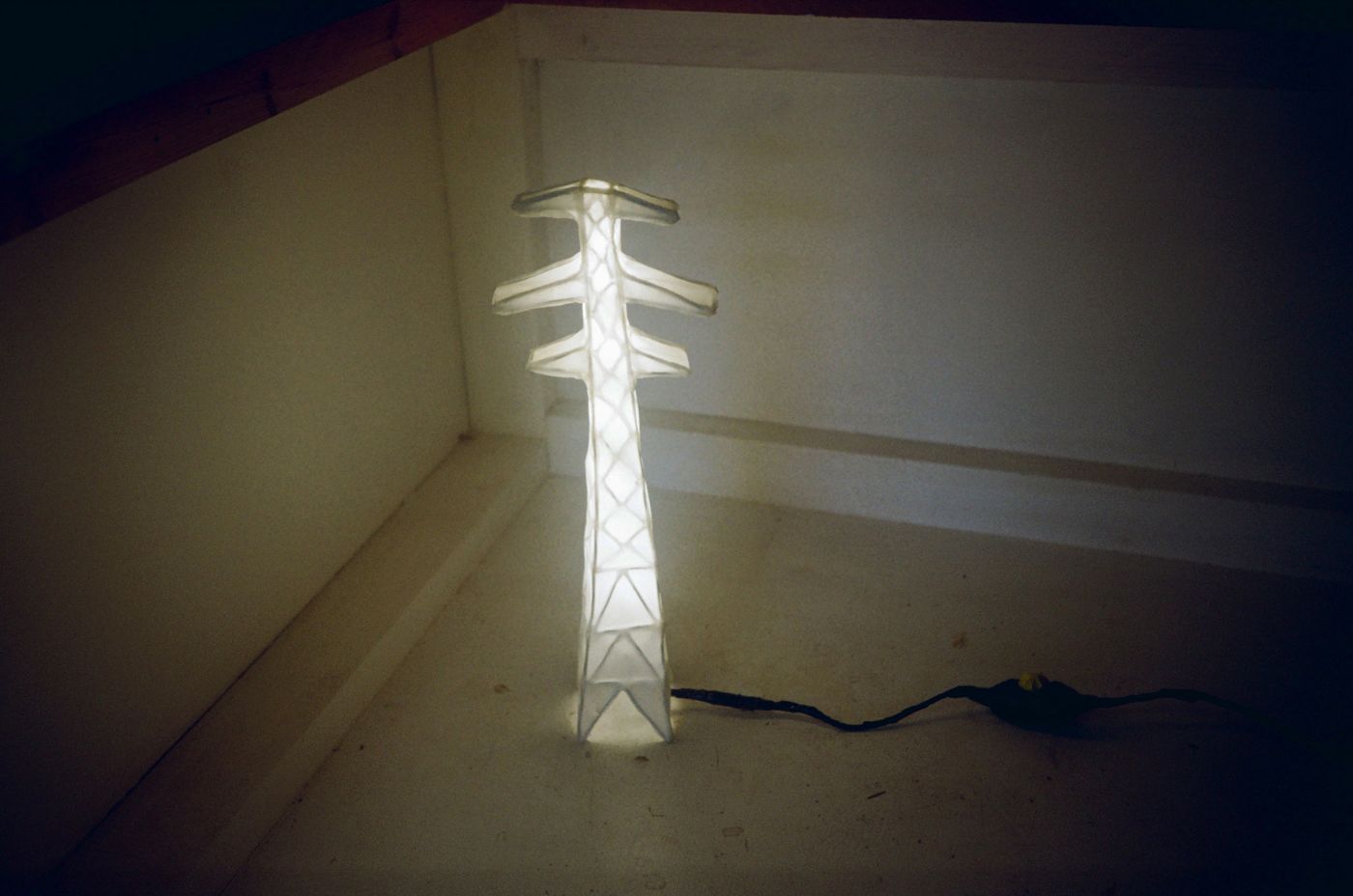Pylon Lamp with three arms glowing in a white corner